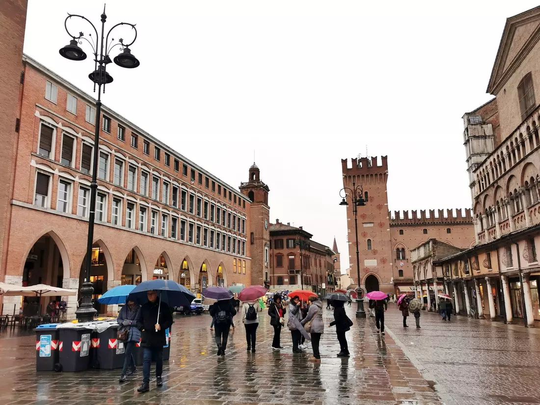 Light drizzle on a quiet street with umbrellas