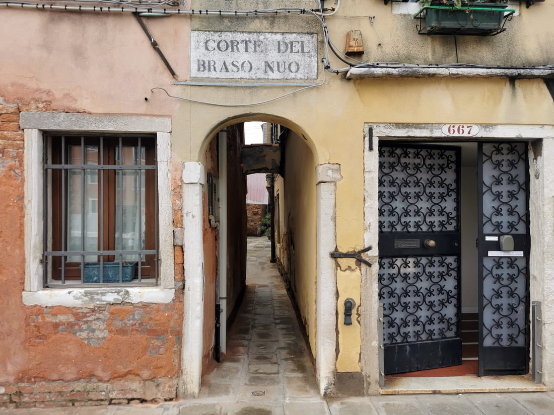 Stone archway leading to a quiet Venetian courtyard