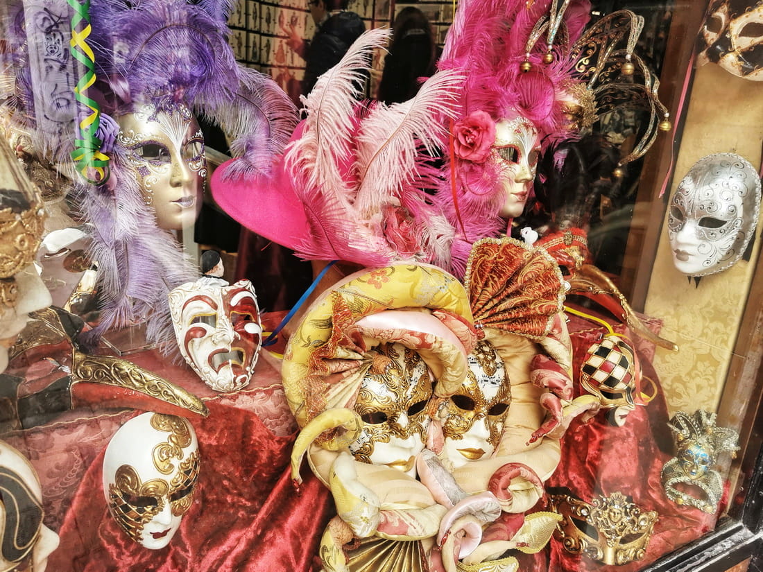 Shop window display of expensive handcrafted Venetian masks with feathers and gold leaf