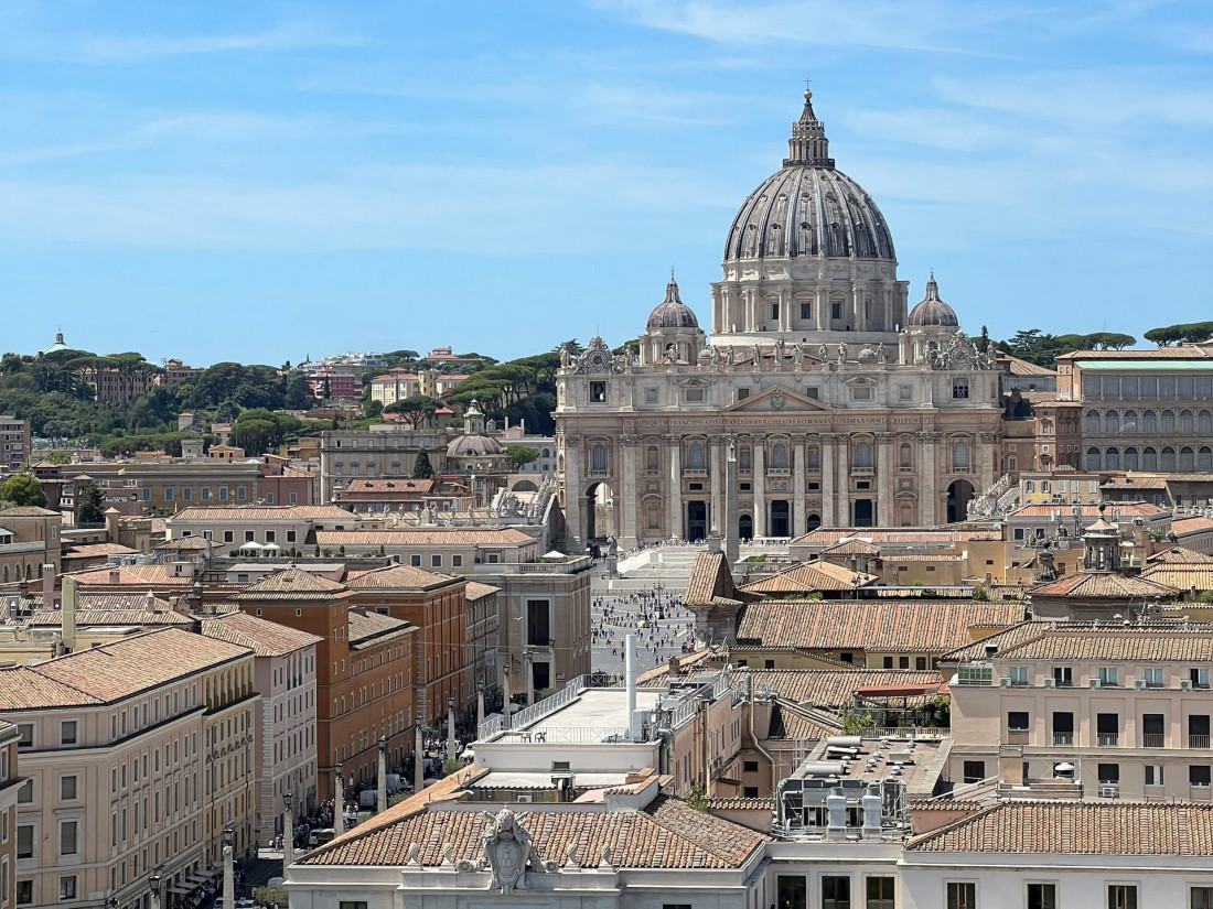 Facade and dome of St. Peter's Basilica in Vatican City against a clear bright blue sky.