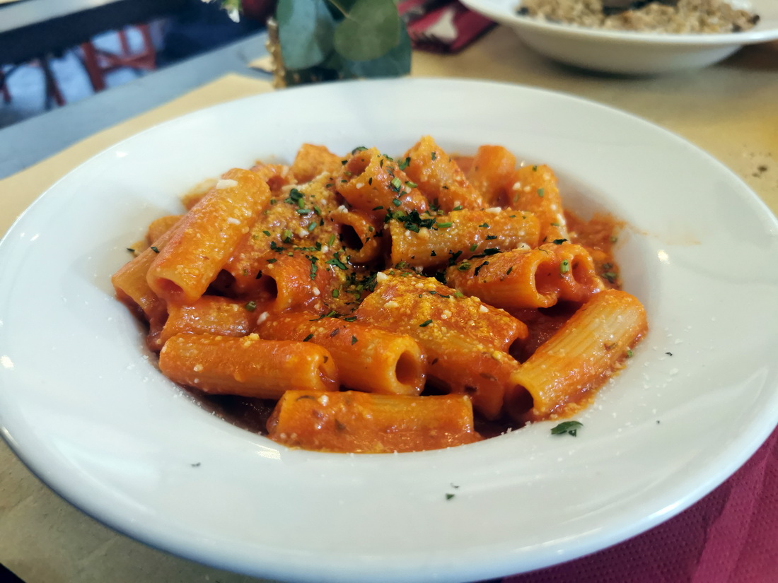 Plate of Rigatoni pasta with red tomato sauce served on a white plate in a Roman restaurant
