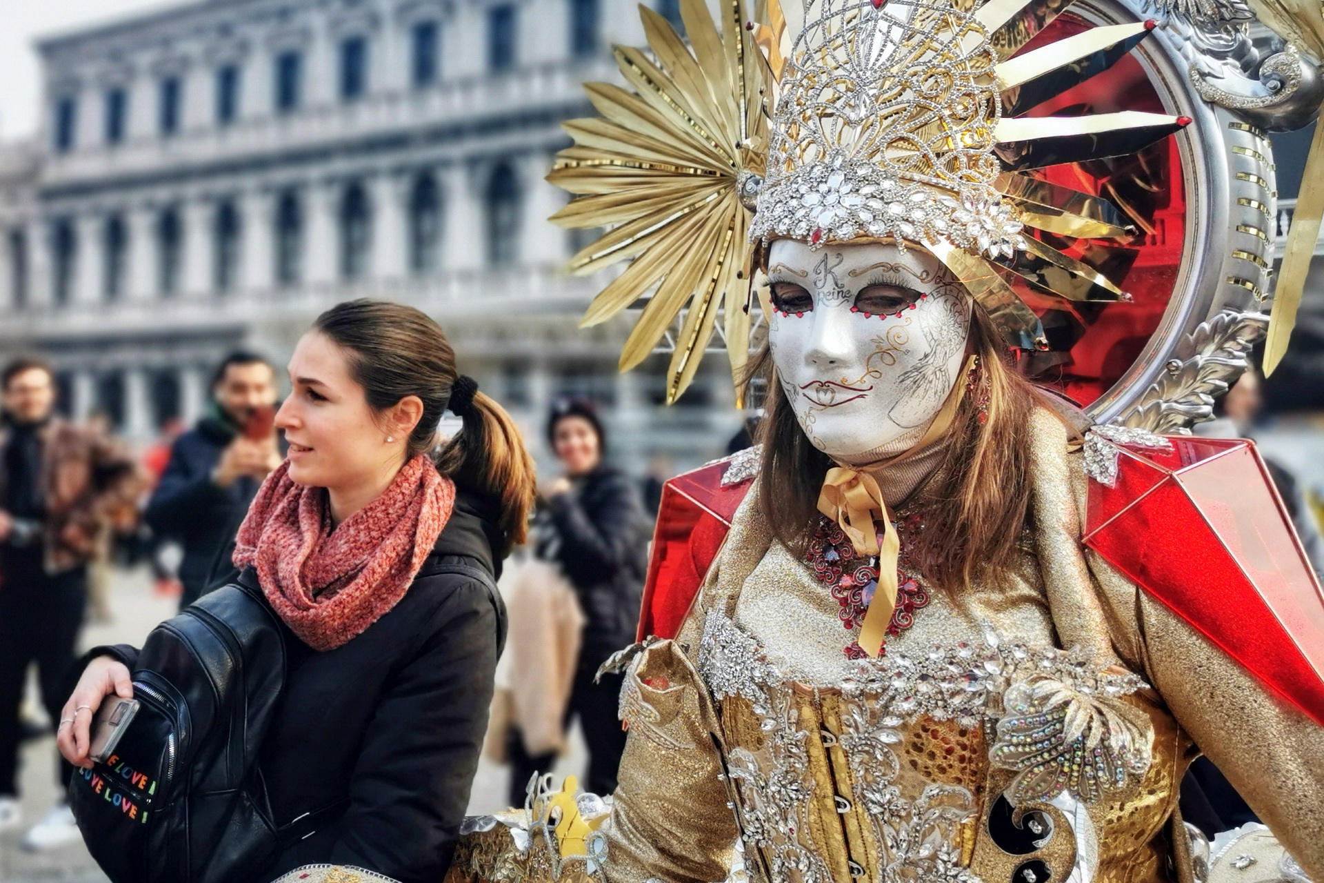 Venetian Carnival participant in a massive red and gold structure costume surrounded by tourists