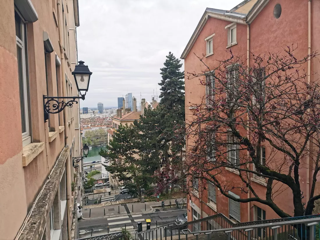 A view from a steep staircase in Lyon, with historic facades in the foreground and modern high-rises in the distance.