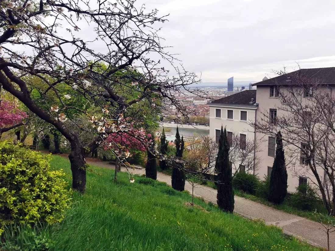 Footpath through Parc des Hauteurs with panoramic views of Lyon and the Basilica of Notre-Dame de Fourvière in the distance.