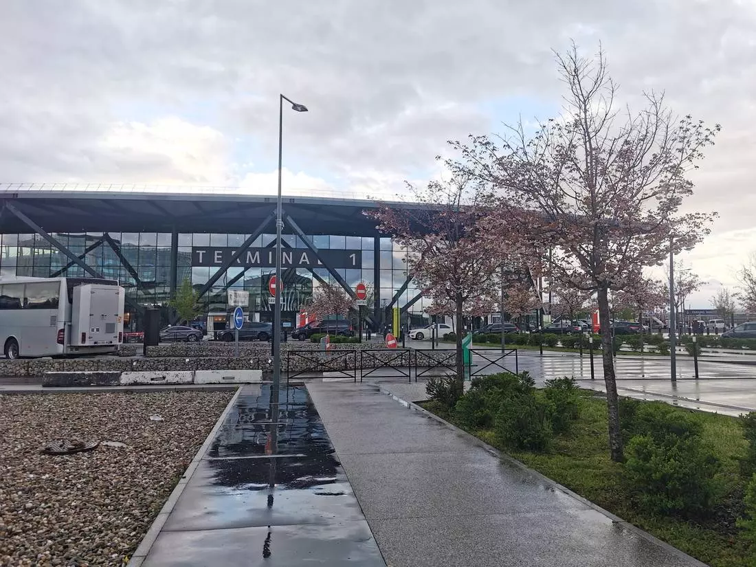 Exterior view of Lyon-Saint Exupéry Airport, showing the modern architecture of the terminal and a calm atmosphere outside.