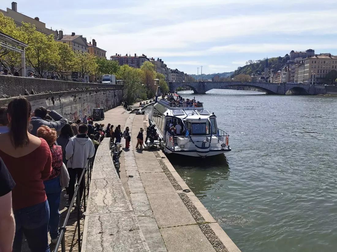 A sunny day on the Saône, with a long line of people waiting for a river cruise in central Lyon.