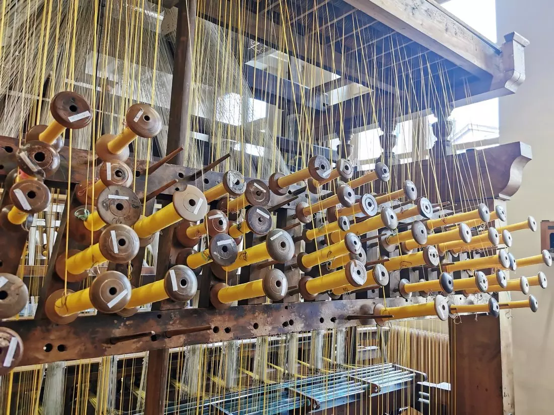 Jacquard loom in motion during a silk weaving demonstration at Atelier de Soierie in Lyon.