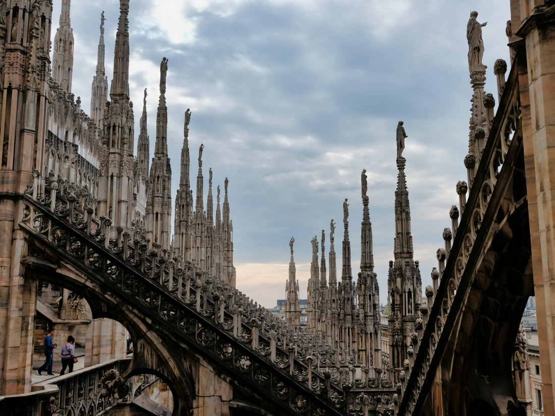 Milan Duomo rooftop terraces featuring a forest of Gothic spires and flying buttresses made of Candoglia marble