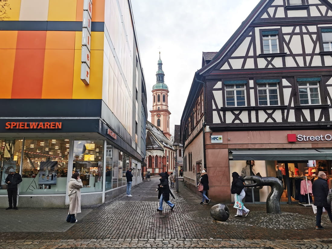 Modern drugstore Müller next to a historic half-timbered building in Offenburg city center, illustrating the blend of commerce and tradition.