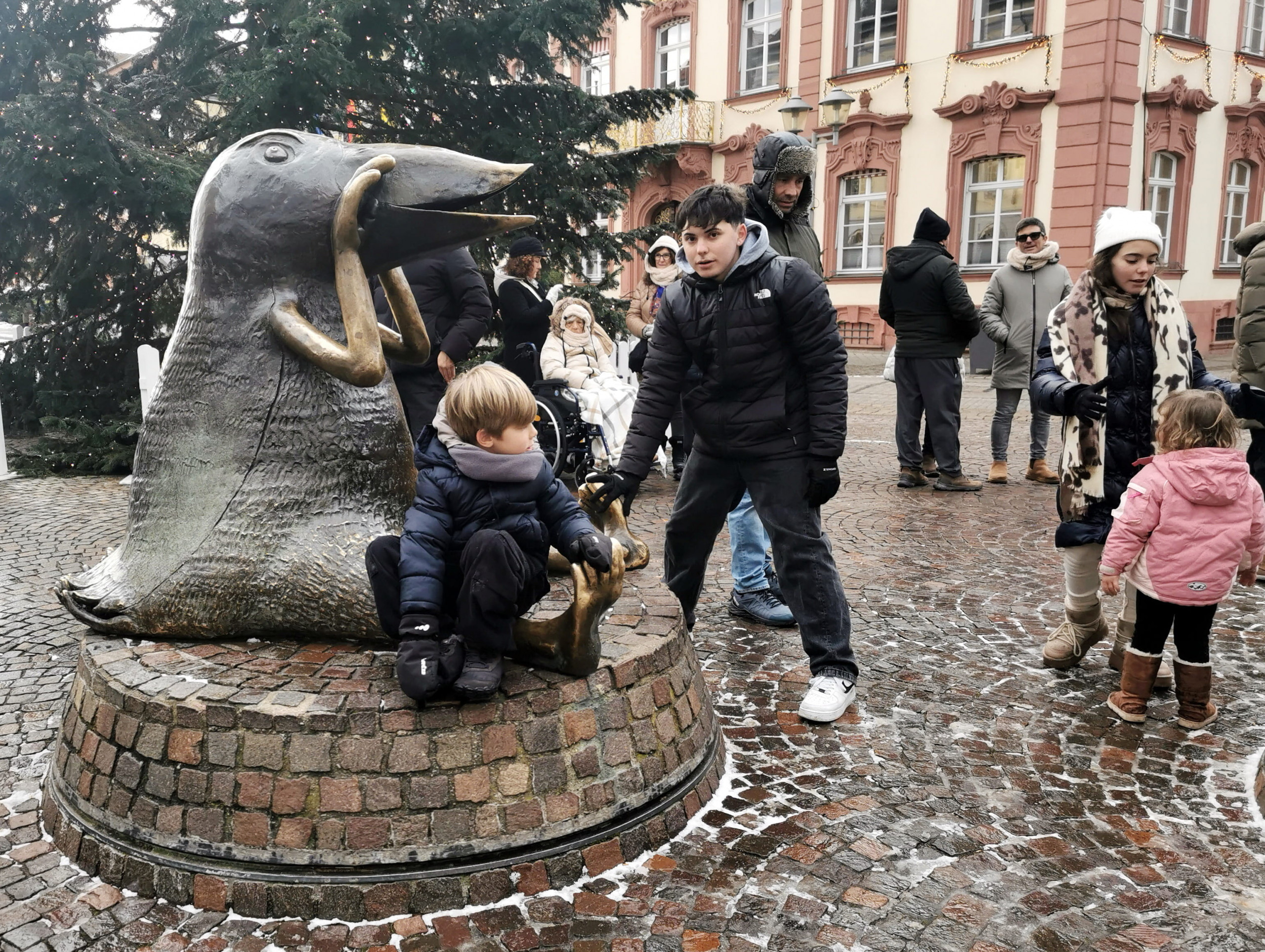 Children playing on the bronze 'Werres Birds' sculptures in Offenburg's market square, with the town hall in the background.