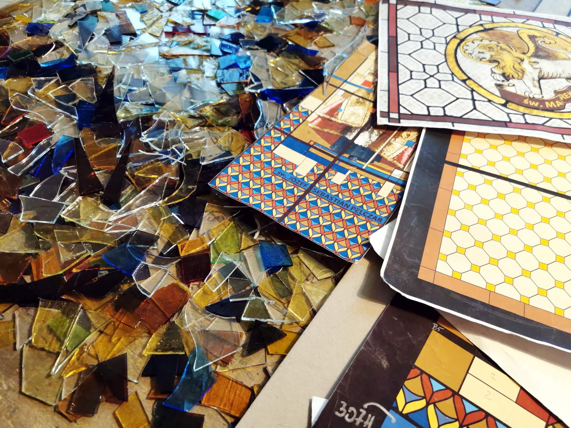 stained glass fragments and paper templates on a workshop table