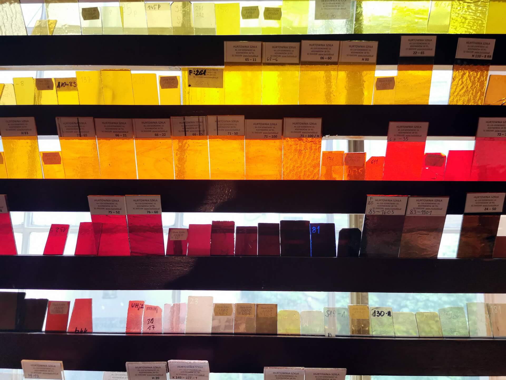 rows of coloured glass sheets stored on workshop shelves